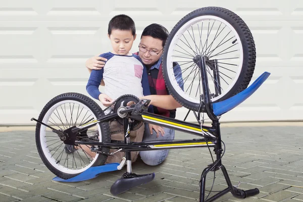 El hombre y su hijo reparan una bicicleta en casa — Foto de Stock