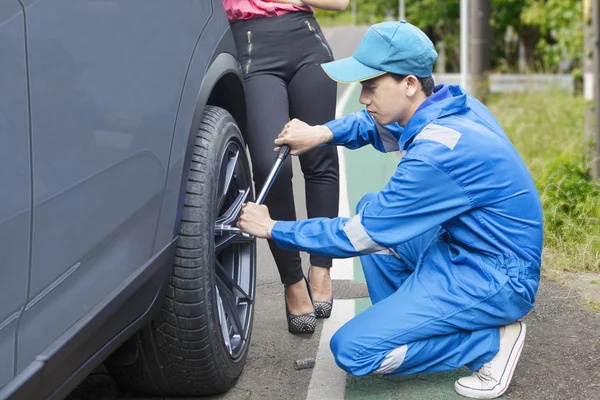 Bilmekaniker byta ett däck på vägen — Stockfoto