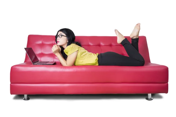 Modelo femenino con portátil soñando despierto en sofá — Foto de Stock