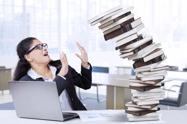 Werkneemster heeft een stapel vallende boeken — Stockfoto