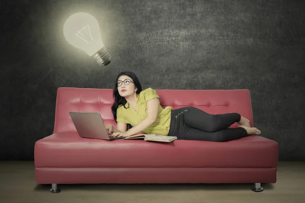 Girl looking at lamp and uses laptop — Stock Photo, Image