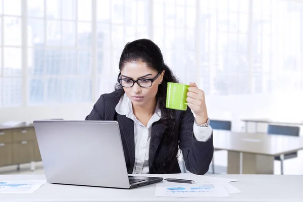 Indian employee drinks coffee while working — Stock Photo, Image