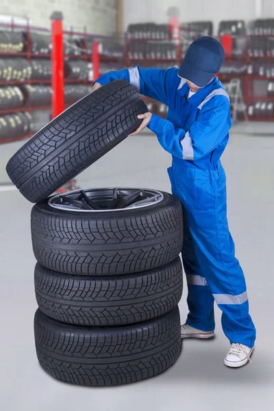 Mecánico hace una pila de neumáticos — Foto de Stock
