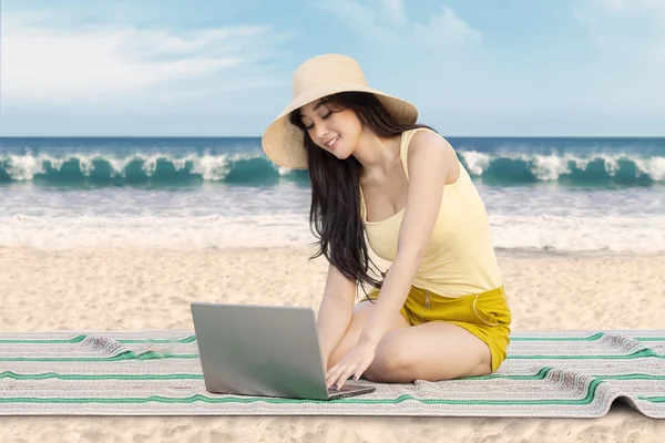 Chica bonita usando el ordenador portátil en la playa — Foto de Stock