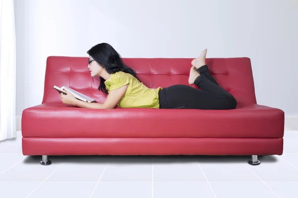 Žena si číst knihu na gauči — Stock fotografie