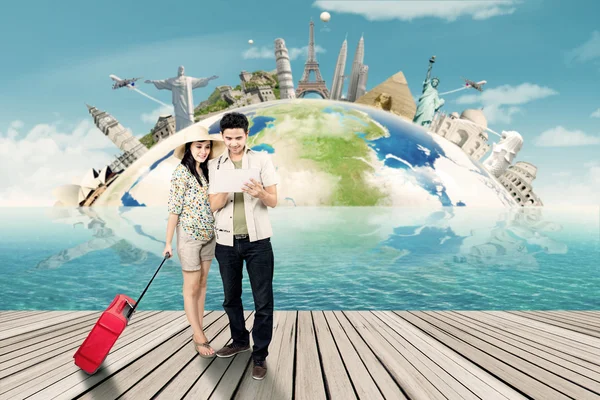 Two tourists look at world map on tablet — Stock Photo, Image