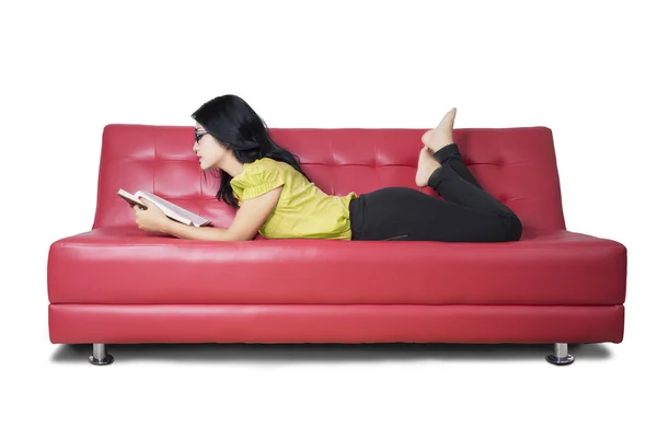 Femme décontractée lit un roman sur le canapé Image En Vente