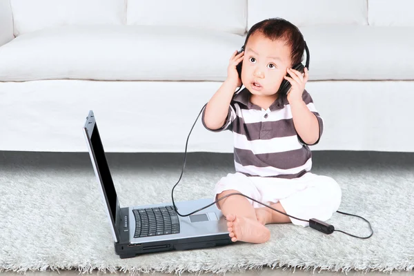 Baby hoofdtelefoon dragen en het gebruik van laptop — Stockfoto