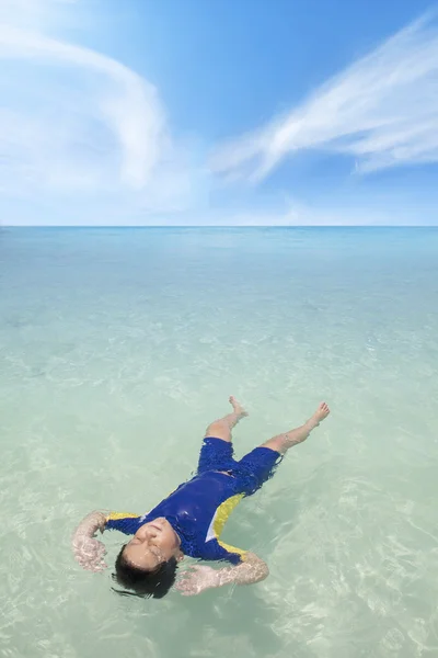 Menino nadando e flutuando na praia — Fotografia de Stock