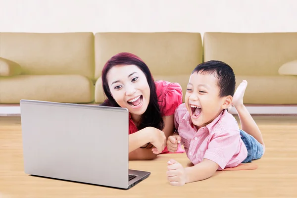 Alegre chico y su madre usando portátil — Foto de Stock