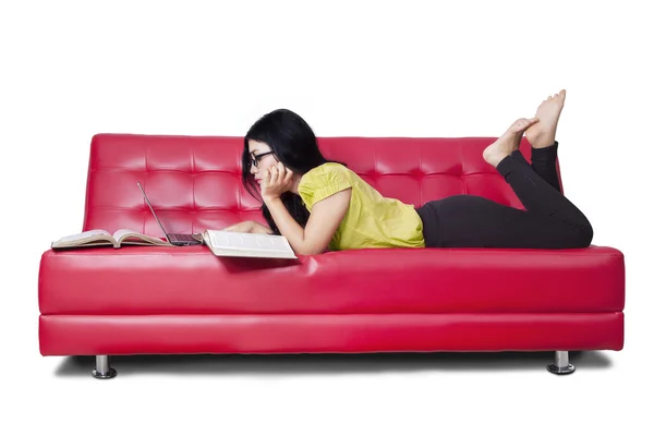 Estudante do sexo feminino estudando e lê livros no sofá — Fotografia de Stock