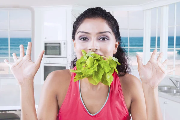 Modelo femenino comiendo espinacas en la cocina — Foto de Stock