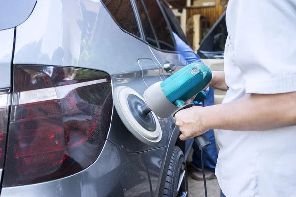 Hands polish a car with polishing machine