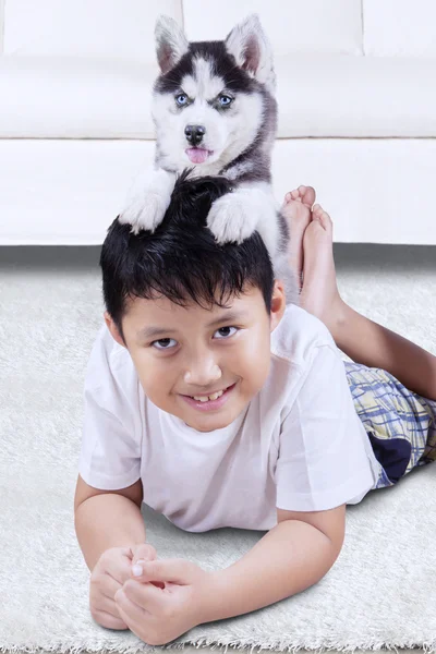 Jongen liggend op het tapijt met husky hond — Stockfoto