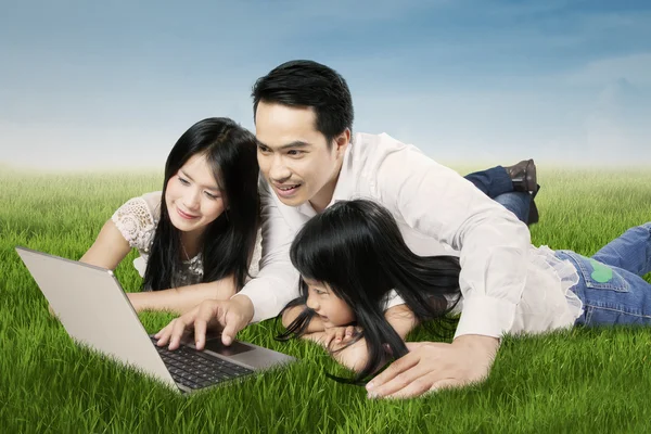 Азиатская семья использует ноутбук в природе — стоковое фото