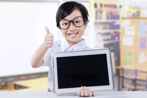 Menina segura tablet e mostra polegar para cima na classe — Fotografia de Stock