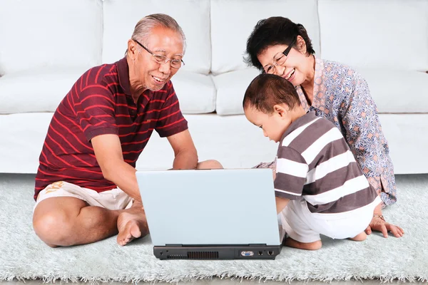 Grands-parents avec bébé utilisant un ordinateur portable — Photo
