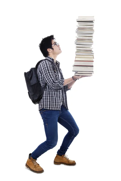 Studente maschio che trasporta una pila di libri — Foto Stock