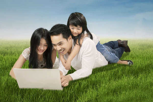 Vrolijke familie laptop spelen op veld — Stockfoto