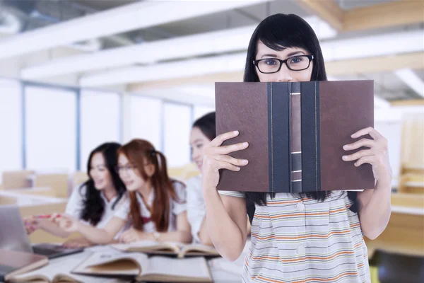 Estudiante sostiene un libro con sus amigos discutiendo —  Fotos de Stock