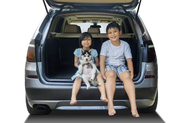 Två barn och husky hunden i bilen — Stockfoto