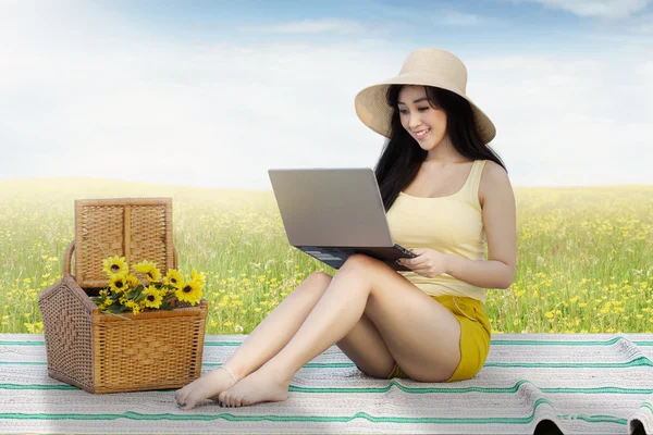 Bellissimo modello femminile utilizza notebook sul campo — Foto Stock