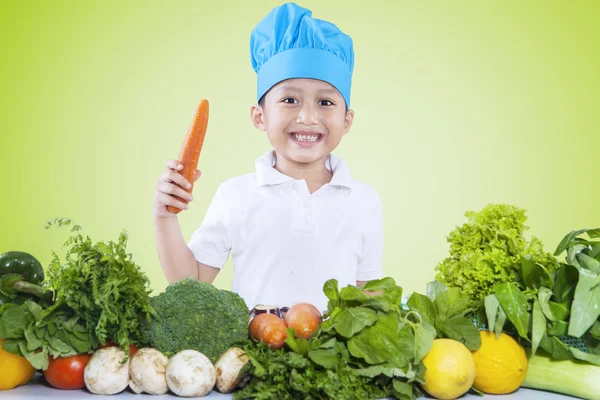 Niño sostiene zanahoria mientras prepara verduras —  Fotos de Stock