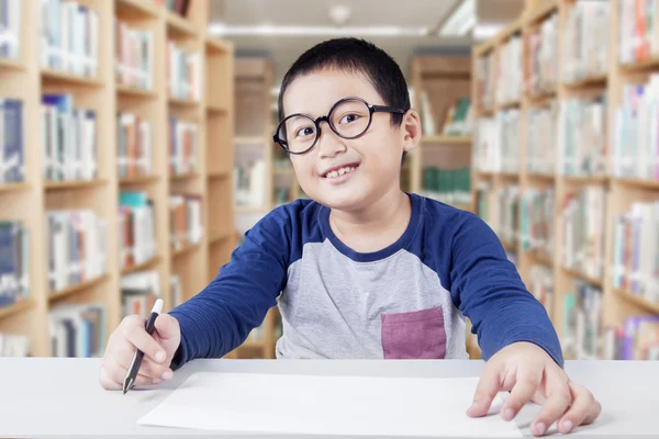 Skolpojke håller papper och markör i biblioteket — Stockfoto