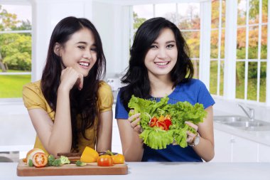 Taze salata gösterilen iki neşeli kız