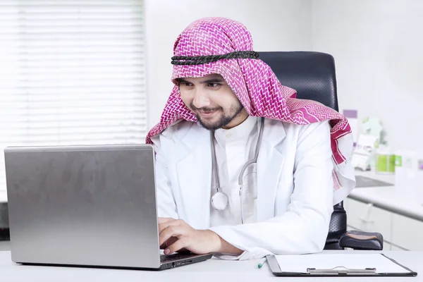 Arabský lékař pomocí přenosného počítače na stole — Stock fotografie