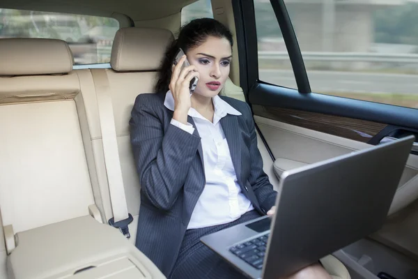 Busy Indian businesswoman working in car — Stock Photo, Image
