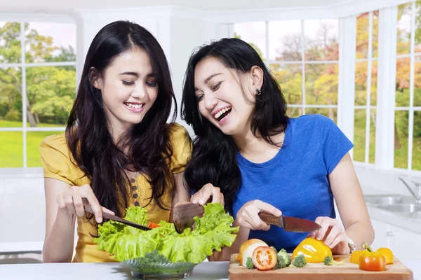 Glada kvinnor matlagning sallad i kök — Stockfoto