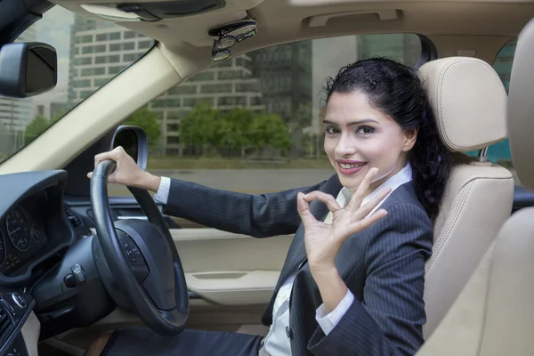 Mujer india conduciendo un coche y muestra señal OK — Foto de Stock