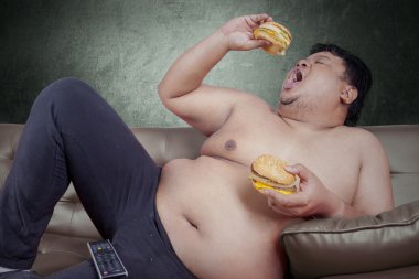 Aç obez adam iki hamburger yiyor