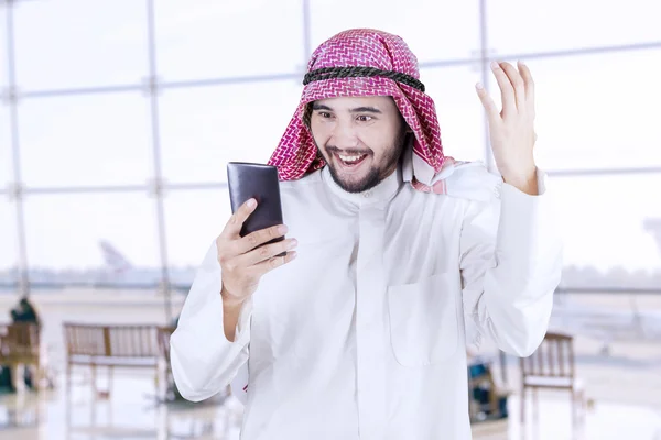 Trabajador árabe feliz utiliza el teléfono celular en el aeropuerto —  Fotos de Stock