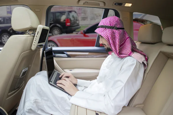 Arabiska affärsman fungerar med laptop i bilen — Stockfoto