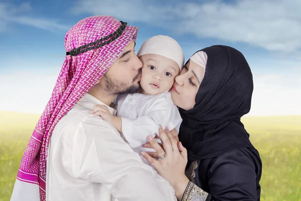Arabische Familie küsst ihr Kind im Park — Stockfoto