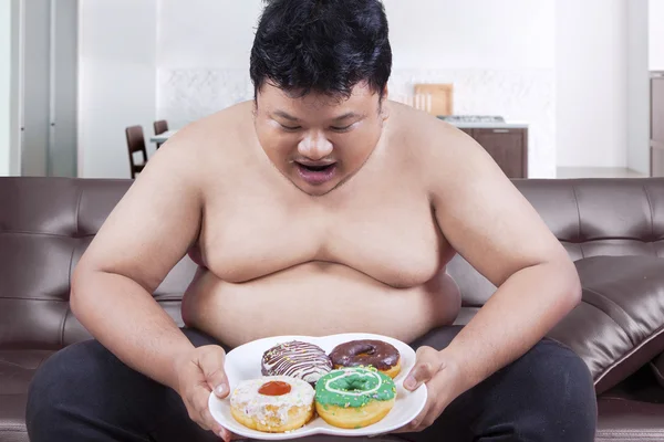 Homem faminto segurando um prato de donuts — Fotografia de Stock