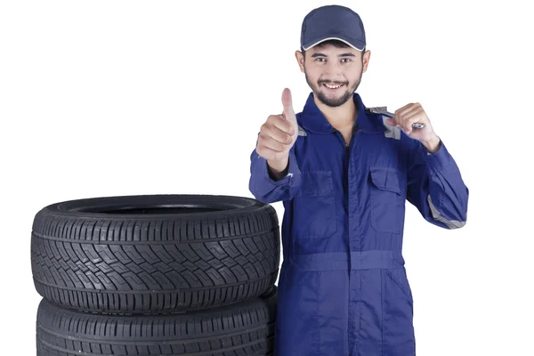 Mecânico com pneus mostra polegar para cima — Fotografia de Stock