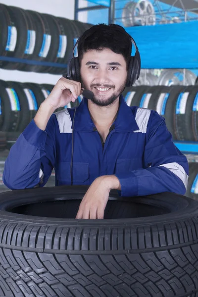 Giovane meccanico che indossa auricolari in officina — Foto Stock