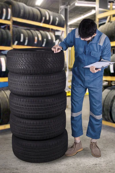 Mecânico árabe verifica os pneus na oficina — Fotografia de Stock