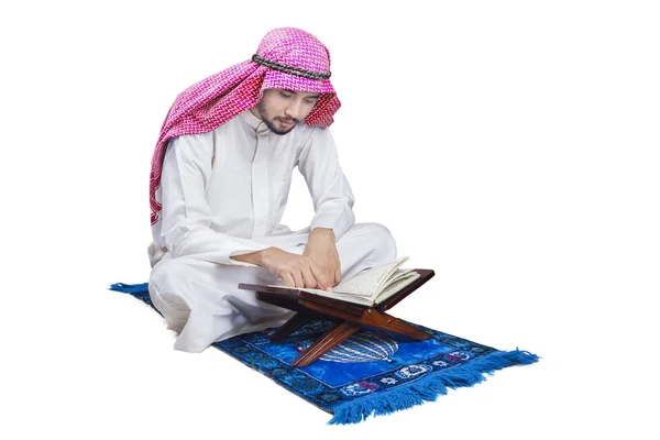 Homem árabe lê Alcorão no estúdio — Fotografia de Stock