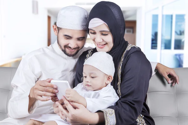 Família muçulmana feliz usar celular em casa — Fotografia de Stock
