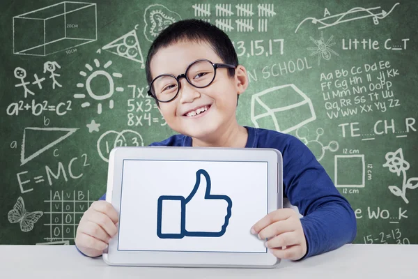 Little schoolboy with thumb up in class — Stock Photo, Image