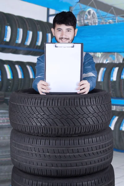 Mannelijke monteur houdt lege Klembord in werkplaats — Stockfoto