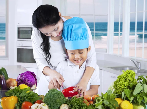 Mujer enseña a su hijo a cortar verduras —  Fotos de Stock