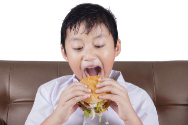 Çocuk bir çizburger ısırmaya hazır
