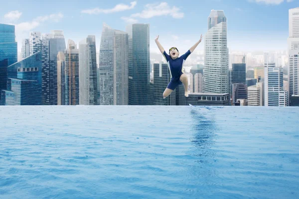 Pojken hoppar på poolen på skyskrapa på taket — Stockfoto