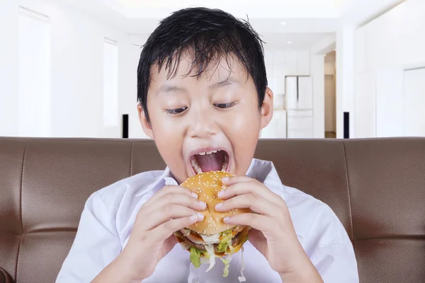 Sevimli çocuk, evde hamburger ısırmaya hazır