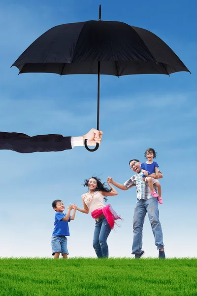Rodina skok na louce pod deštníkem — Stock fotografie